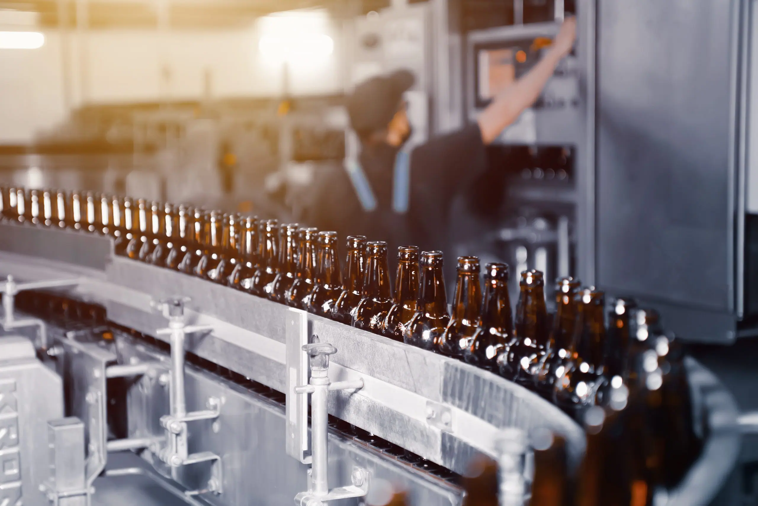 Primer plano de botellas de cerveza de vidrio de color marrón en la línea transportadora de embotellado de cerveza