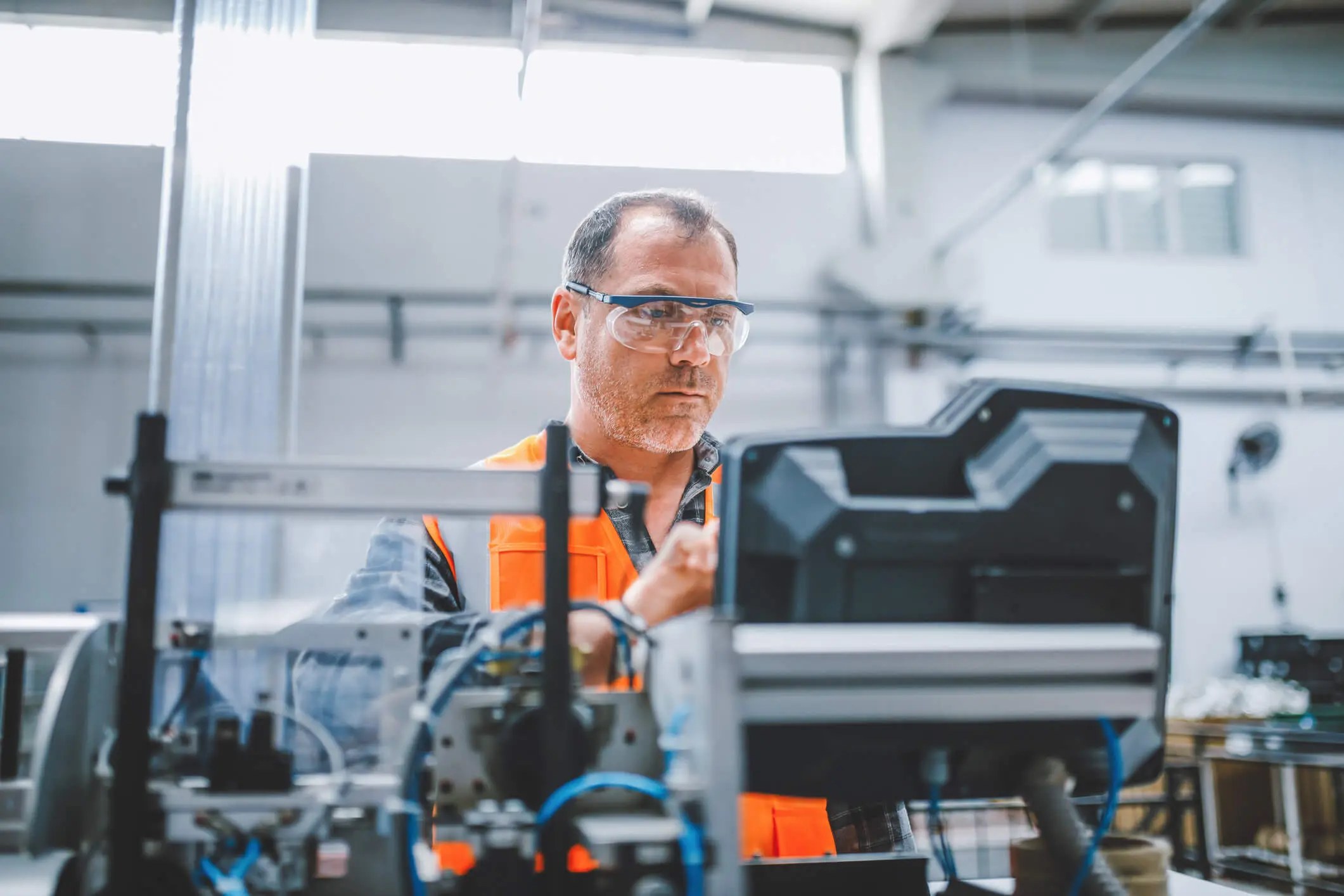 Empleado de una fábrica industrial profesional trabajando con piezas de máquinas poniendo, verificando y probando cables de equipos industriales en un gran almacén de fábrica de la planta de fabricación de cables y alambres electrónicos eléctricos