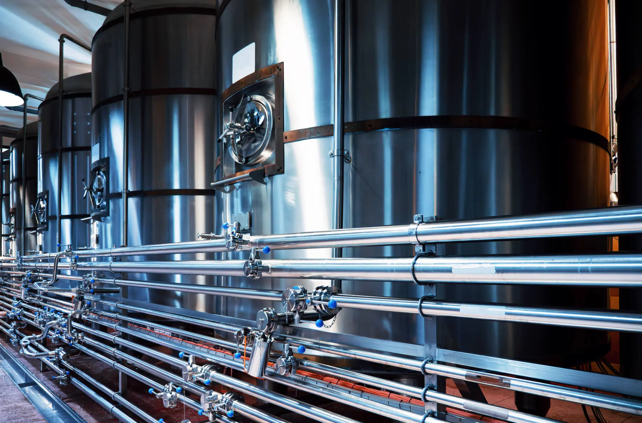 Tanques modernos de acero para cervecerías y tuberías intrincadas, precisión y calidad en la producción de cerveza artesanal.